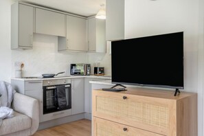 Eine kompakte Küche mit Flachbildfernseher, Mikrowelle und Kaffeemaschine.