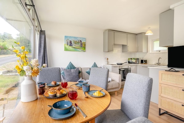 A modern kitchen with white cabinets, a dining area with a round table, and a painting on the wall.
