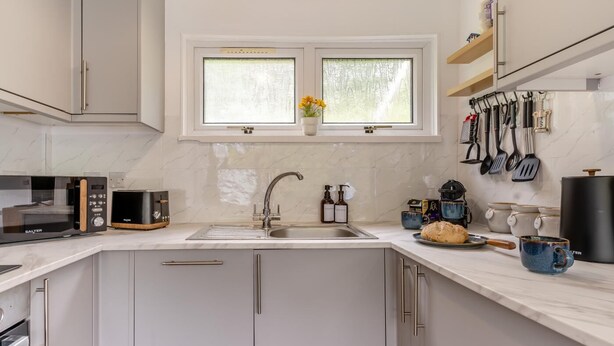 A modern kitchen with a built-in microwave, a sink, and various utensils on the wall. - 2 Bed in Caswell Bay (oc-s45738) (Newton)