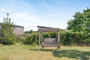 A wooden swing set in a grassy outdoor area with a building in the background. - 2 Bed in Awre (oc-o45277) (Awre)