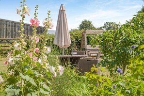 A garden with a table and chairs, a pergola, and a wooden fence.
