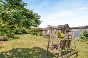 A wooden swing set in a backyard with a house in the background.