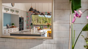 A modern kitchen with a large island, pendant lighting, and a view of the outdoors. - 5 Bed in Marhamchurch (oc-p45735) (Marhamchurch)
