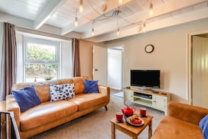 A cozy living room with a leather sofa, a television, and a table with a red teapot and cups. - 3 Bed in Maxworthy (oc-s45407) (Maxworthy)