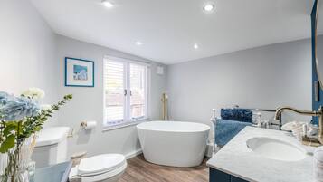 A modern bathroom with a freestanding bathtub, a toilet, and a sink.
