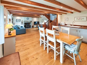 A spacious living area with a wooden dining table, white chairs, and a kitchen area with white cabinets and a wooden countertop. - 3 Bed in Slaggyford (oc-h44976) (Slaggyford)