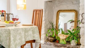 Uma sala de jantar com uma mesa posta para dois, parede de pedra e espelho com moldura dourada.
