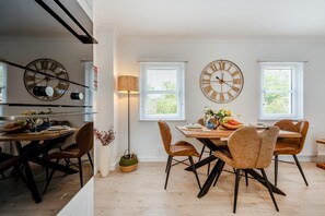 A dining area with a wooden table, chairs, and two wall clocks. - 1 Bed in St. Dogmaels (oc-m45322) (Saint Dogmaels)