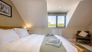 Een slaapkamer met een bed, een raam, een stoel en een radiator.