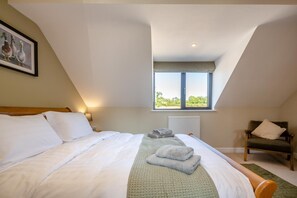 Ein Schlafzimmer mit Bett, Fenster, Stuhl und Heizkörper.