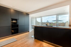 Eine moderne Küche mit integrierten Geräten, einem großen Fenster und Blick ins Freie.