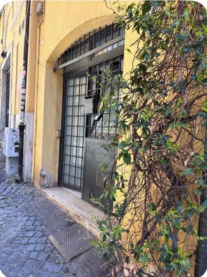 Ein Gebäude mit gelber Fassade, einem Metallgitter und einer kleinen Stufe zum Eingang.