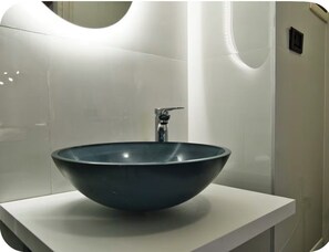 Ein modernes Badezimmer mit einem großen, dunkel gefärbten Waschbecken auf einer weißen Arbeitsplatte.