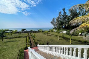 A landscaped garden with a view of the sea, a white balustrade, and a variety of trees. - Kisuri White House - Luxury Beach Home in Mfangano with A/C (Homa Bay County)
