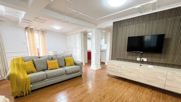 A modern living room with a grey sofa, wooden flooring, and a mounted TV.