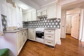 Una cocina con armarios blancos, un salpicadero estampado y un horno empotrado.