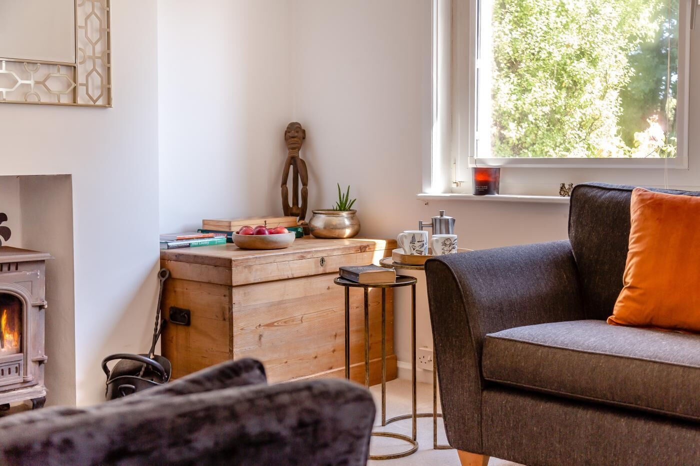 Una sala de estar acogedora con chimenea, un sofá, una mesa de centro y una ventana con vistas a la vegetación.