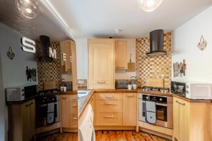 Une cuisine compacte avec des meubles en bois, une cuisinière à gaz, un four à micro-ondes et un grille-pain.