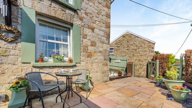 A stone building with a window, a door, and a small outdoor seating area with chairs and a table. - 2 Bed in Upper Cwmtwrch (oc-s45449) (Cwm-twrch Uchaf)