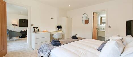 Een moderne slaapkamer met een groot bed, een bureau en een stoel.