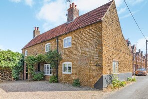 A stone house with a red-tiled roof, a brick chimney, and a gravel driveway. - 3 Bed in Snettisham (oc-d45398) (Snettisham)