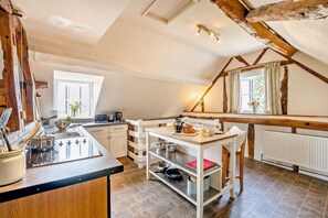 A kitchen with a wooden table, a coffee machine, and a kettle. There is a window with curtains and a radiator. - 2 Bed in Cradley (oc-s45721) (Cradley and Storridge)