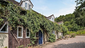 A rustic building with a wooden exterior, a blue door, and a gravel driveway. - 1 Bed in Cradley (oc-s45723) (Cradley and Storridge)