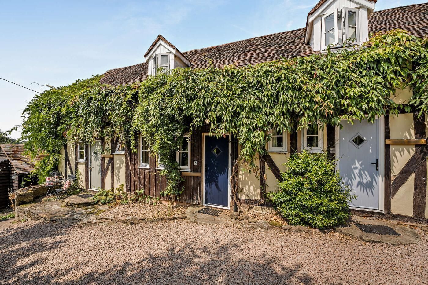 Une maison traditionnelle avec un porche couvert, une porte bien visible et une allée gravillonnée.