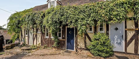 Ein traditionelles Haus mit überdachter Veranda, einer sichtbaren Tür und einer Schotterauffahrt.
