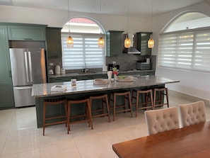 Una cocina moderna con una isla central, taburetes de bar y una mesa de comedor.