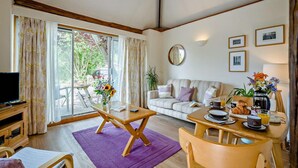 A furnished living room with a sofa, a dining table with breakfast items, a television, and a large window with curtains. - 1 Bed in Cradley (oc-c45724) (Cradley and Storridge)