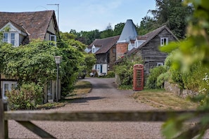 A rural village street with traditional houses, a gravel path, and a red telephone booth. - 1 Bed in Cradley (oc-w45725) (Cradley and Storridge)