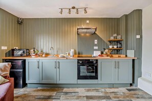 A kitchen with a built-in oven, microwave, and a coffee machine on the counter. - 1 Bed in Cradley (oc-w45725) (Cradley and Storridge)