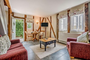 A cozy living room with a fireplace, a dining area with a table and chairs, and a television mounted on the wall. - 1 Bed in Cradley (oc-w45725) (Cradley and Storridge)