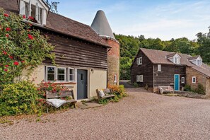 A traditional wooden house with a stone chimney, a gravel driveway, and a bench. - 3 Bed in Cradley (oc-o45726) (Cradley and Storridge)