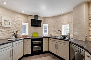 A kitchen with a stone wall backsplash, a built-in oven, a dishwasher, and a window with blinds. - 3 Bed in Cradley (oc-o45726) (Cradley and Storridge)