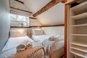 A bedroom with two beds, a window with a plant, and a wooden beam ceiling. - 3 Bed in Cradley (oc-o45726) (Cradley and Storridge)