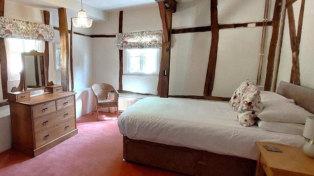 Ein Schlafzimmer mit Bett, Kommode, Stuhl und Fenster.