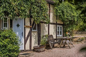 A traditional half-timbered house with a door, windows, and a table with chairs outside. - 2 Bed in Cradley (oc-h45727) (Cradley and Storridge)
