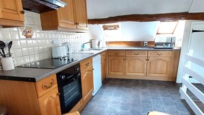 Eine Küche mit Holzausstattung, einem schwarzen Backofen und einer gefliesten Spritzschutzwand.