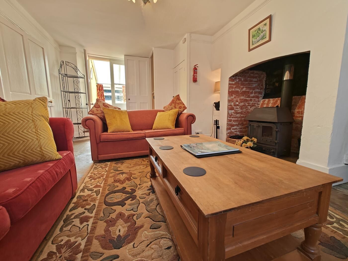 A living room with a red sofa, a wooden coffee table, and a fireplace.