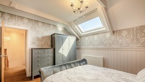 Un dormitorio con cama, armario, radiador y tragaluz.