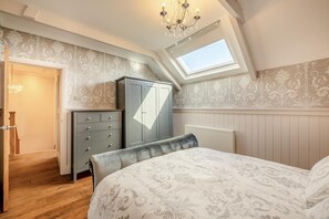 Ein Schlafzimmer mit einem Bett, einem Kleiderschrank, einer Heizung und einem Dachfenster.