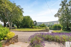 A rural landscape with a stone pathway, lavender bushes, and a grassy area with trees. - 5 Bed in Melmerby (oc-m45569) (Melmerby)