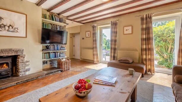 Ein gemütliches Wohnzimmer mit Kamin, Fernseher, Bücherregal und Essbereich mit Tisch für zwei Personen.