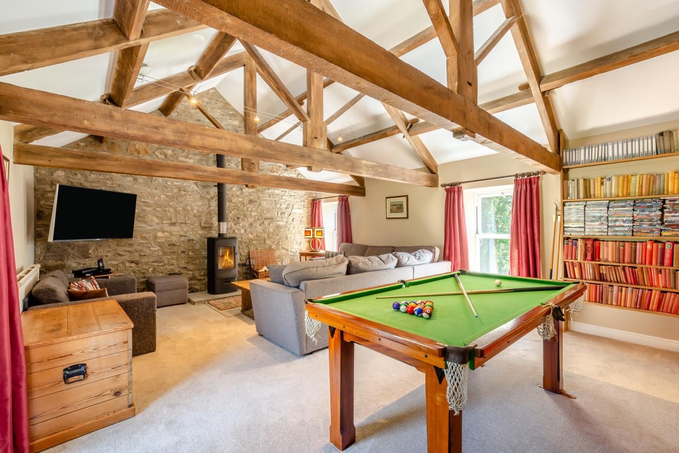 A cozy room with a pool table, a sofa, a fireplace, and a bookshelf.