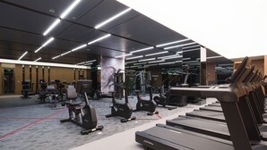 Un gimnasio moderno con cintas de correr, elípticas y equipo de pesas.