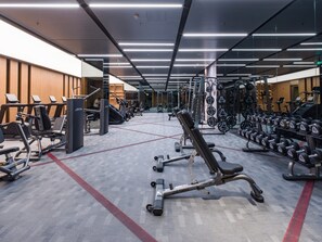 Un gimnasio con equipos de ejercicio variados, incluyendo cintas de correr, máquinas de pesas y pesas libres.