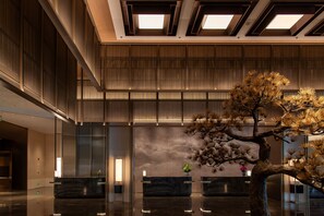 Un vestíbulo moderno con mostrador de recepción, una gran escultura de árbol y un techo con tragaluces.