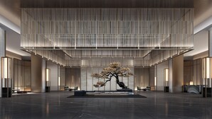 Un hall espacioso con una escultura de árbol central, techos altos y muebles modernos.